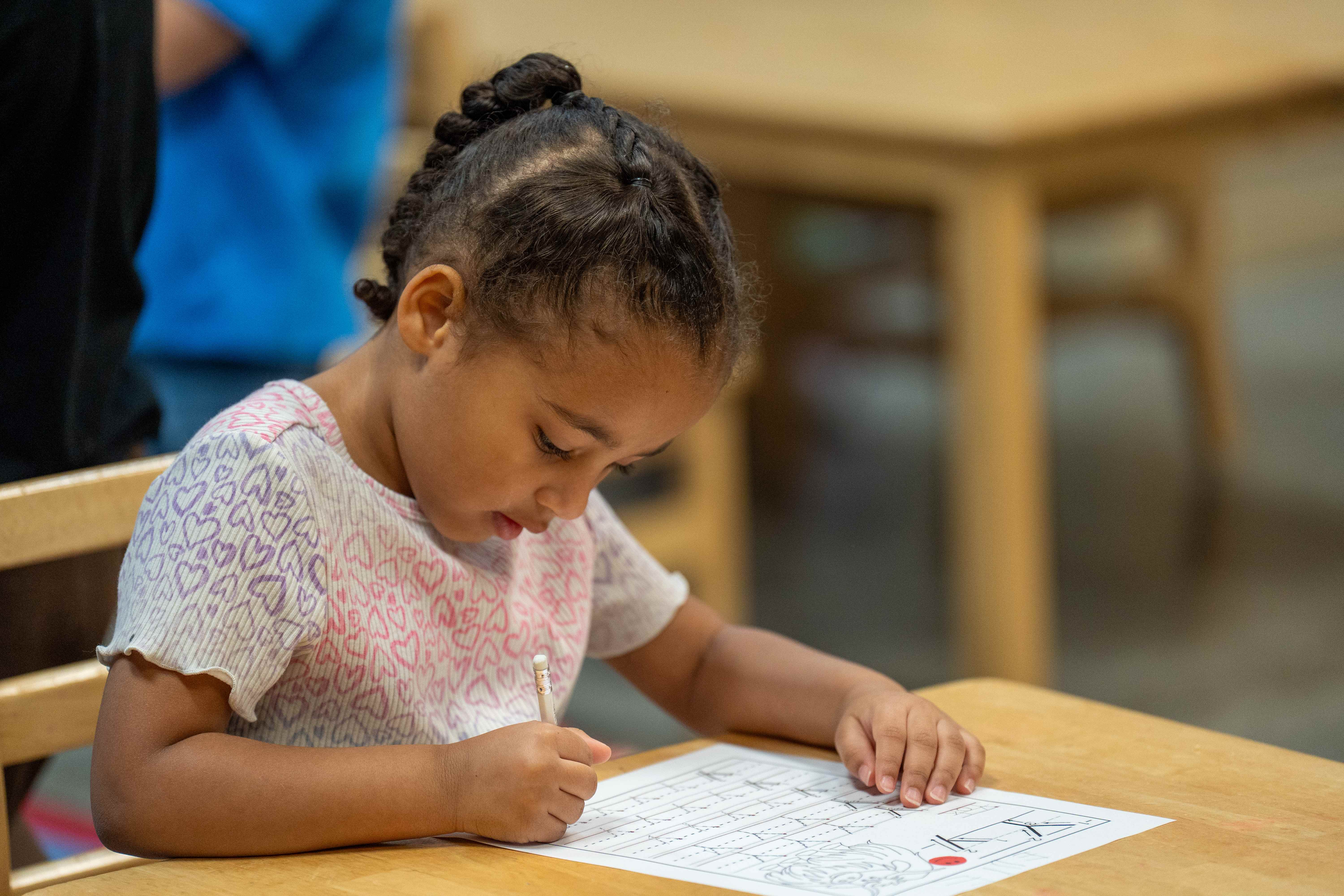 Young girl focused on writing worksheet